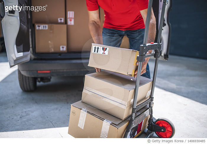 1406930485 | 게티이미지코리아 | Unrecognizable delivery person loading parcels ...